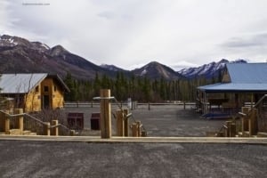 Denali Star Train Depot with wooden structures and surrounding mountains in Denali National Park, promoting travel and tourism in Alaska.