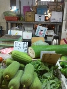Fresh vegetables at a local market, featuring green gourds, leafy greens, and price tags, showcasing the vibrant food culture relevant to travel and culinary experiences.