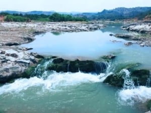 Cilutung River in Majalengka, West Java, Indonesia, featuring flowing water over rocky terrain and lush greenery in the background.