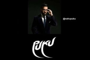 Man in a suit adjusting glasses with the text "PUKU" below, representing a stylish persona.