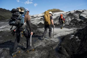 Backpackers trekking across a volcanic landscape in Iceland, equipped with climbing gear and backpacks, showcasing the adventure of backpacking in Iceland.