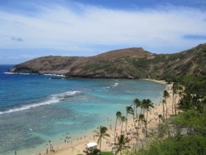 Scenic view of Hanauma Bay in Hawaii, featuring sandy beach, turquoise waters, and lush greenery, ideal for travelers seeking outdoor activities and natural beauty.