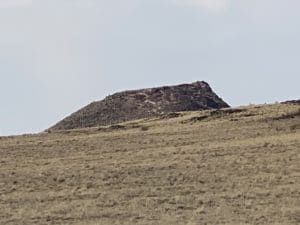 Vulcan Volcano Petroglyph National Monument featuring a prominent volcanic mound against a grassy landscape.