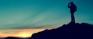 Hiker silhouetted against a colorful sunset, capturing the scenic view, representing adventure and exploration in travel.