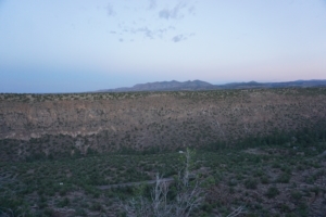 Bandelier National Monument canyon landscape at dusk, showcasing rugged cliffs and expansive desert vegetation, highlighting hiking opportunities and scenic views.