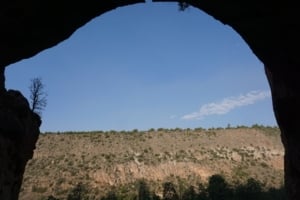 View from the Openn-air Cave Alcove House in Bandelier National Monument, showcasing a rocky landscape and blue sky.