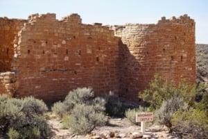Hovenweep Castle ruins showcasing ancient Puebloan architecture, surrounded by desert vegetation and a "Restricted Area" sign, part of Hovenweep National Monument.