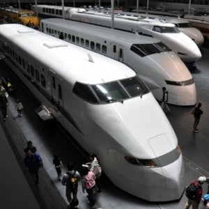 Japanese railway station showcasing Shinkansen bullet trains with travelers exploring the platform, highlighting rail travel in Japan.