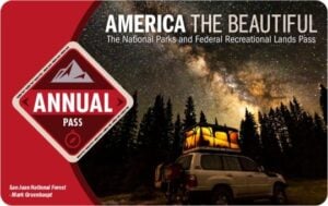 America the Beautiful National Parks and Federal Recreational Lands Pass featuring a scenic night sky, highlighting travel experiences in USA for 2023.