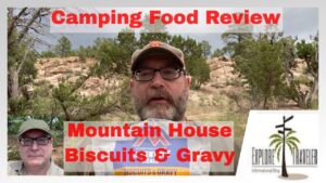 Camping food review featuring a man discussing Mountain House Biscuits & Gravy, with outdoor scenery in the background and ExploreTraveler branding.