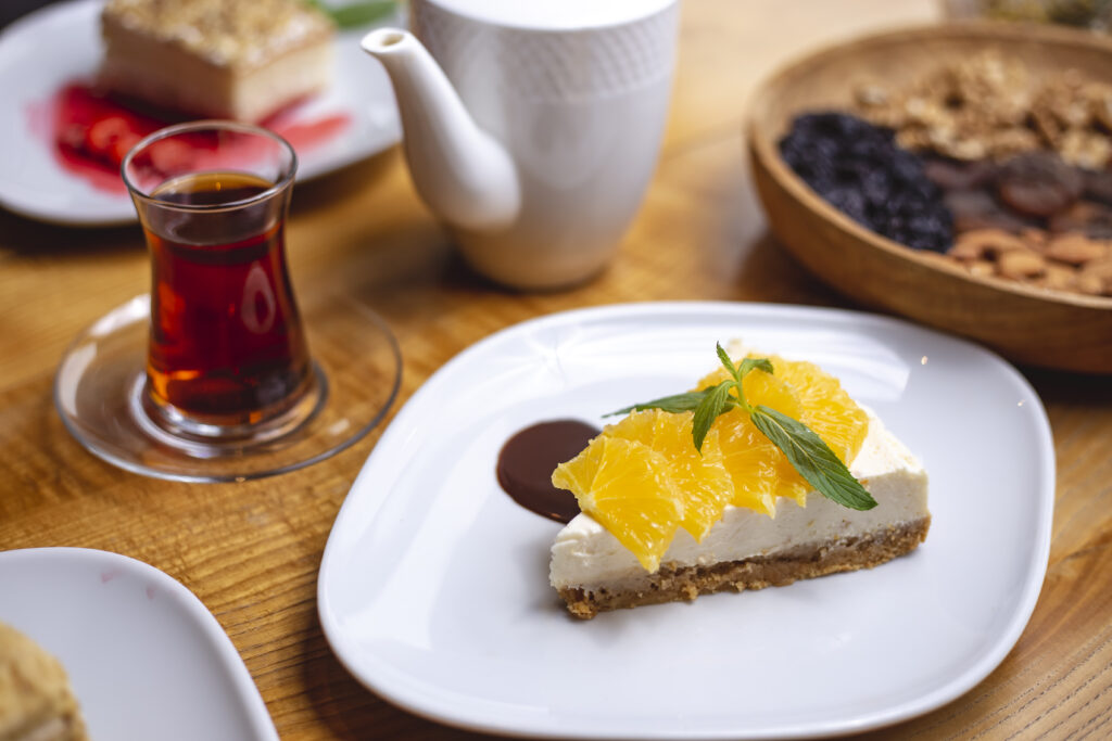 Side-view cheesecake with slices of orange and a glass of tea
