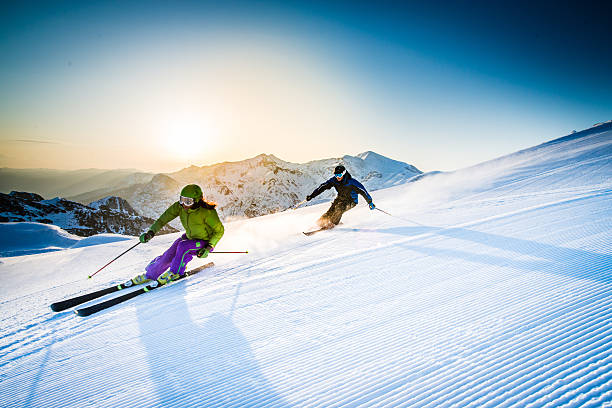 Man and woman skiing downhill at dusk