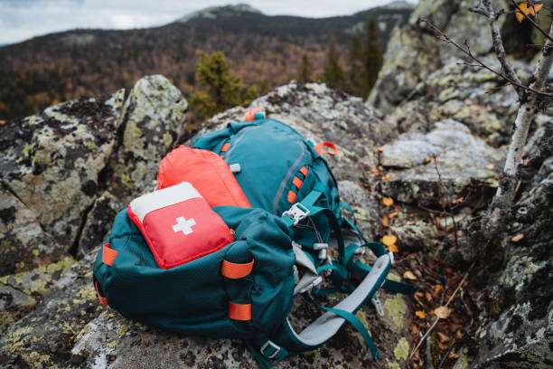 A red hiking first aid kit is on a backpack