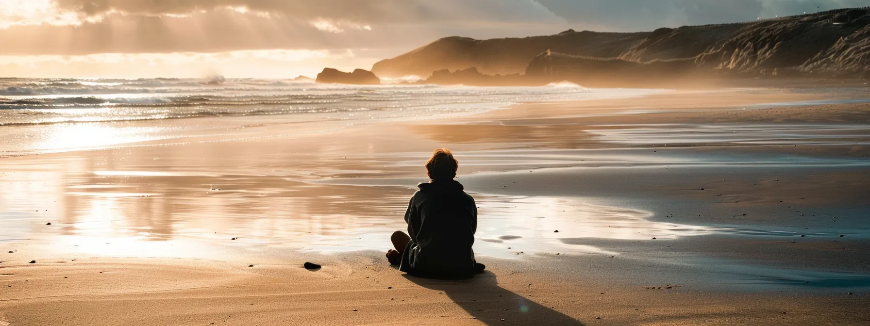 a person sitting alone on a remote beach, contemplating the decision to embrace a nomadic lifestyle.