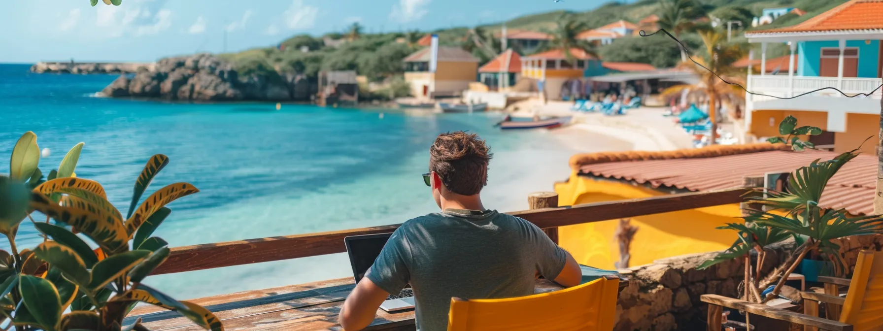 a digital nomad working on a laptop in a vibrant co-working space overlooking a picturesque beach in curaçao.