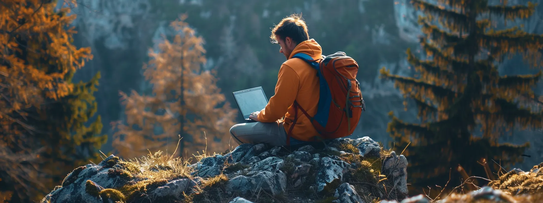 a person with a backpack working on a laptop while sitting in a scenic outdoor location.