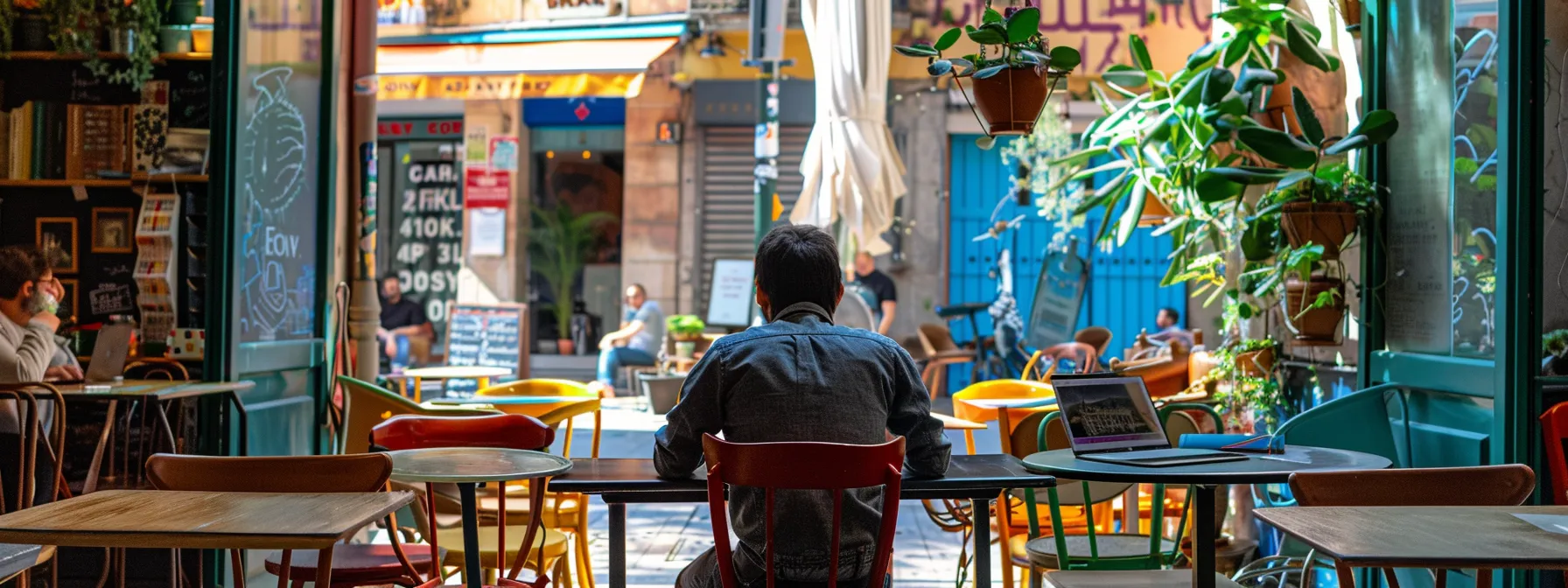 a person sitting at a vibrant cafe in spain, browsing through cost of living data on a laptop.